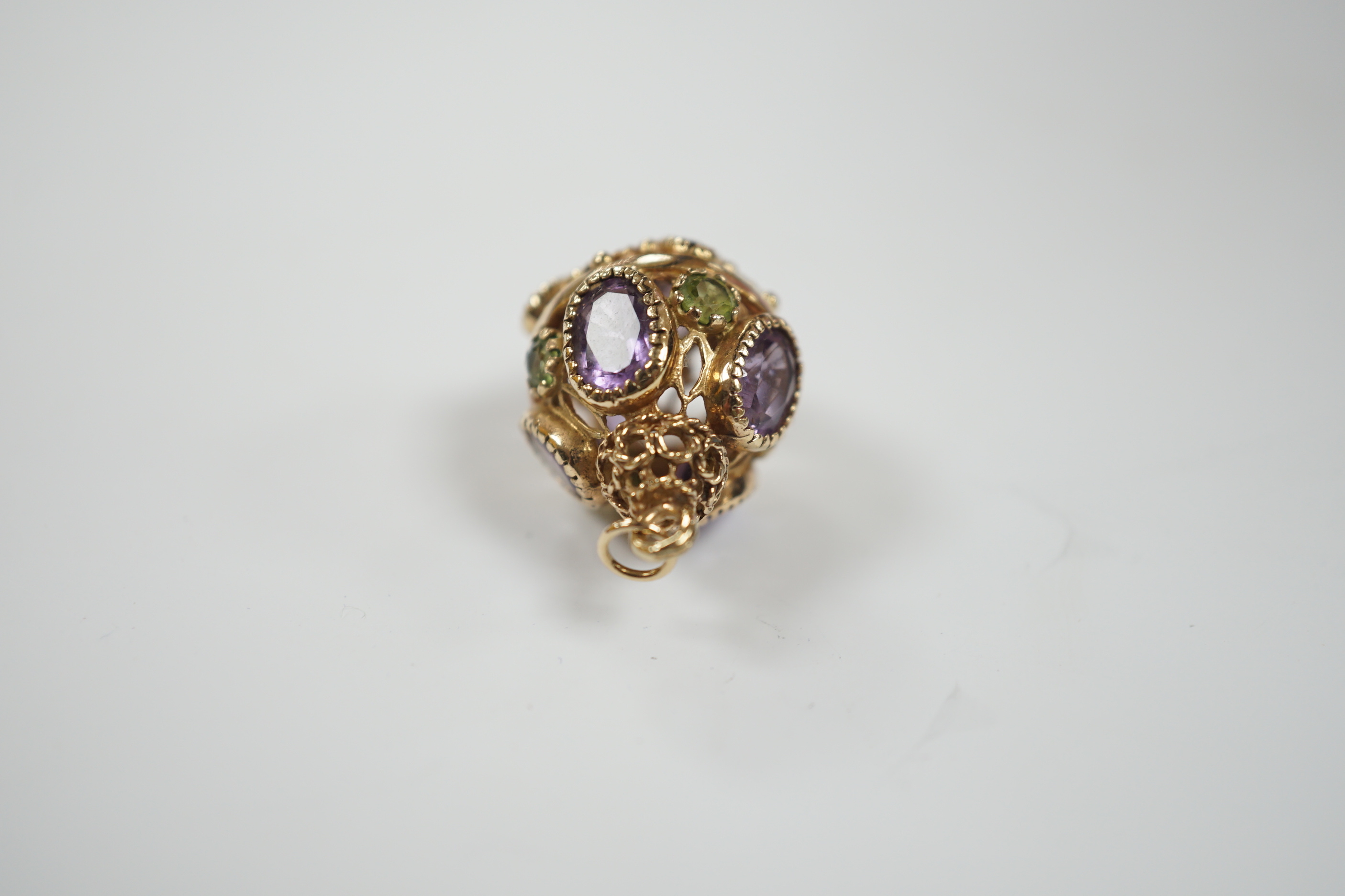 A modern 9ct gold, amethyst and peridot set pendant, or pierced spherical form, 25mm, gross weight 7.5 grams.